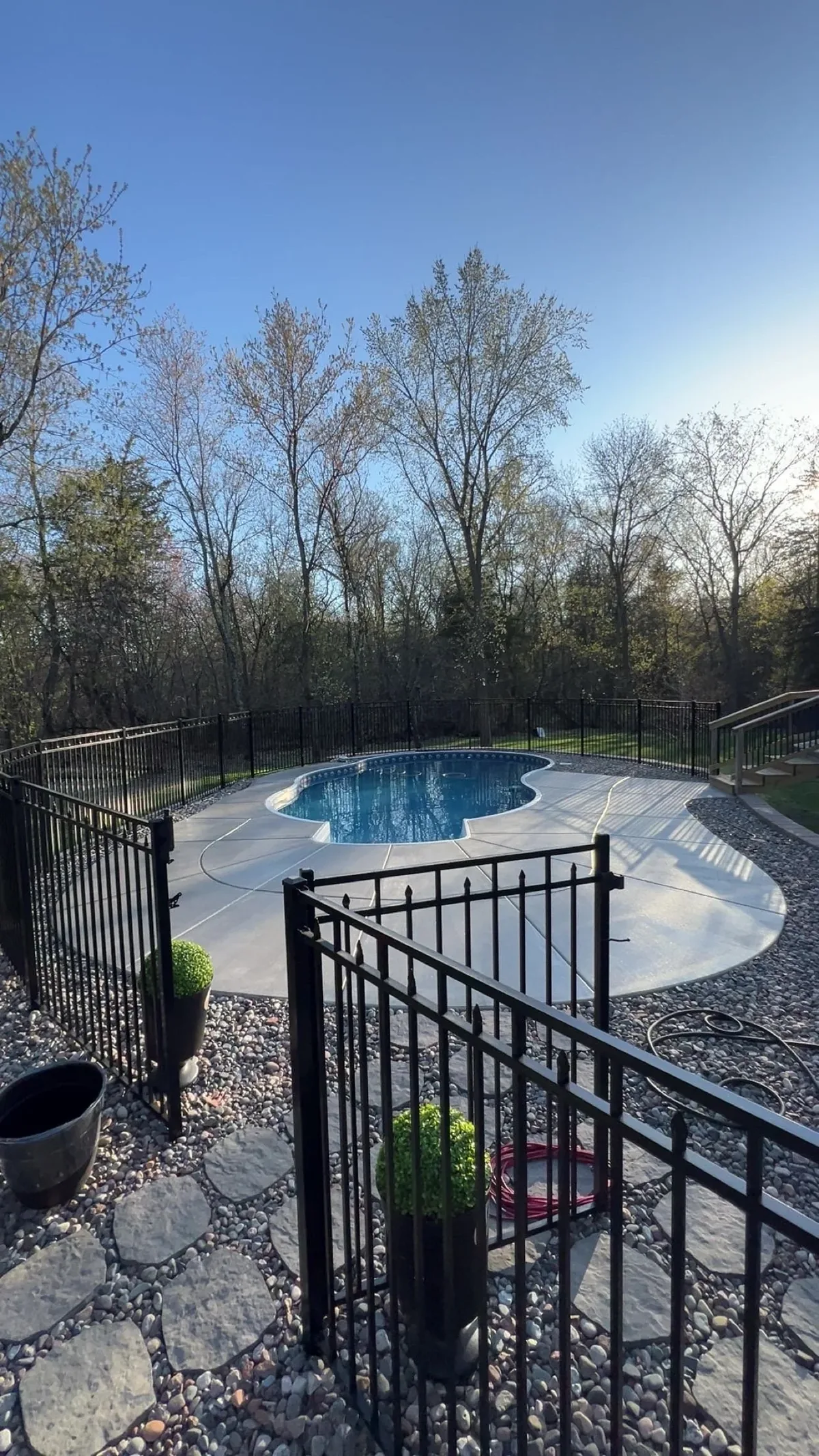 Fenced backyard pool with a new broom-finished concrete deck poured by CBC Custom Concrete