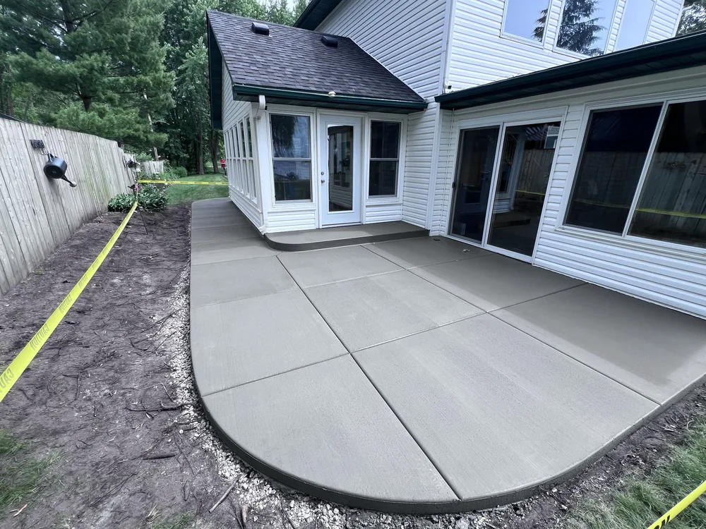 Curved broom-finished patio poured behind a two-story white house