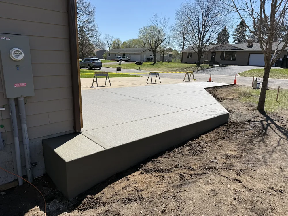 Raised concrete slab and apron freshly poured beside a house on a residential street