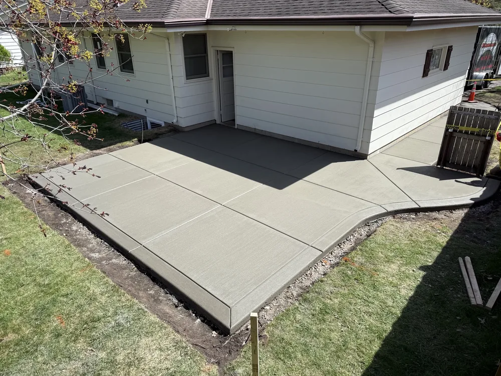 Broom-finished backyard patio and walkway wrapping a white single-story home