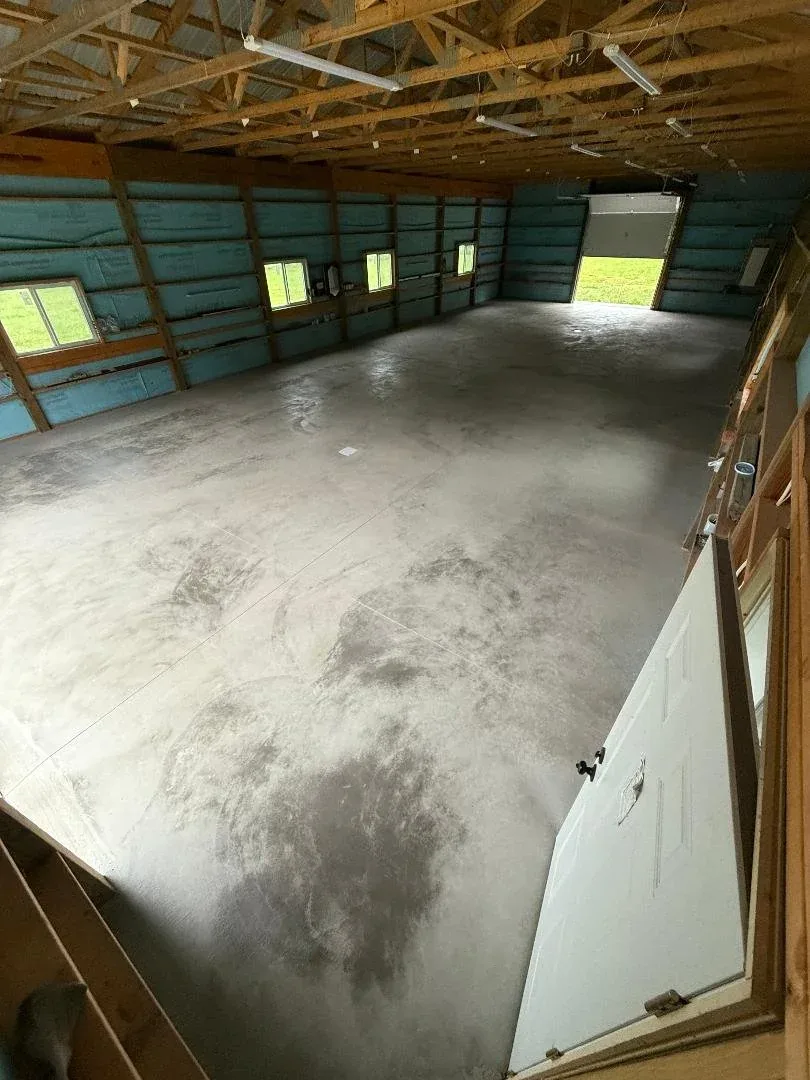 Smooth finished concrete floor inside a newly built pole barn with wood framing