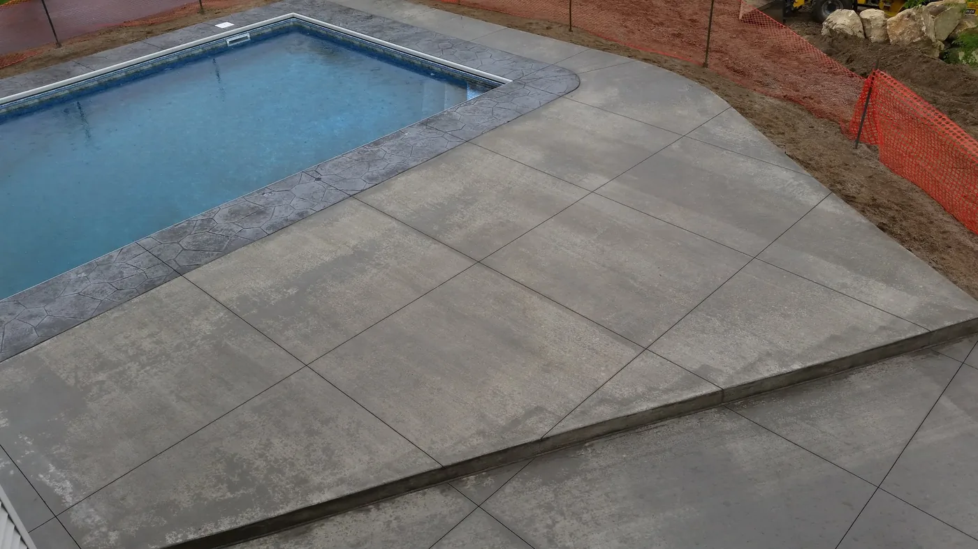 Aerial view of a broom-finished pool deck with a stamped flagstone border around a rectangular pool