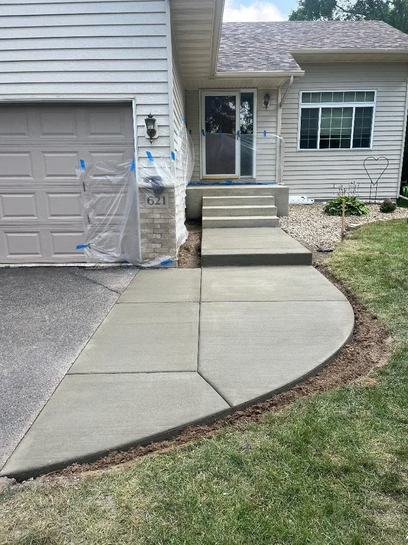 New concrete front steps and a curved sidewalk leading to a home's front entry